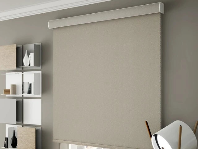 Cortina roller blackout beige con cenefa instalada en dormitorio en Chile, ideal para oscurecimiento total y control de luz.